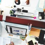 Overhead view of multiple office desks and screens showing a busy operating environment.