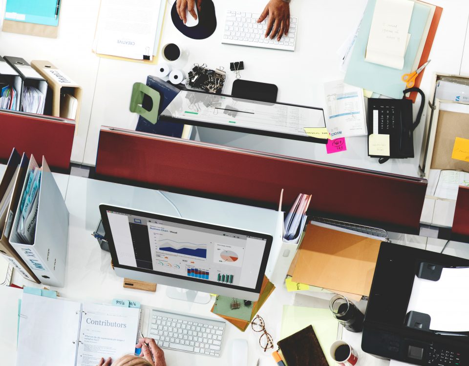 Overhead view of multiple office desks and screens showing a busy operating environment.