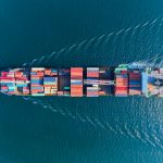 Aerial view of a container ship carrying freight containers across the sea.